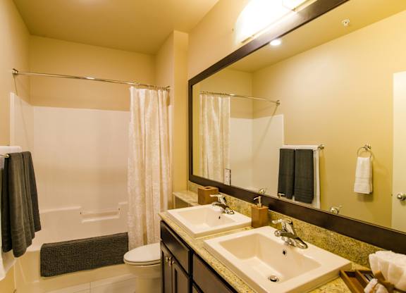 A bathroom with a sink, mirror, and shower.