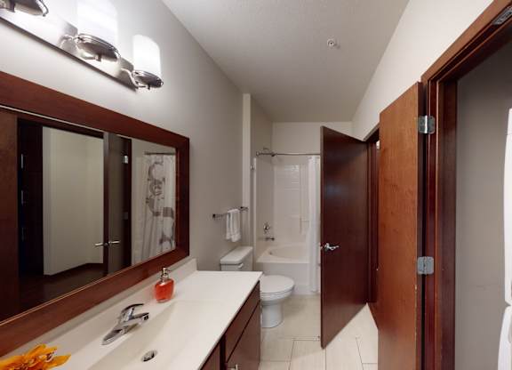 A bathroom with a toilet, sink, and mirror.