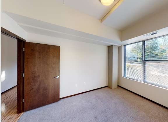 A room with a brown door and a window with blinds.
