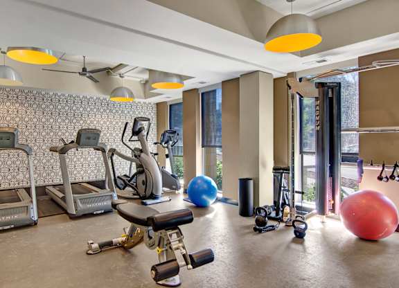 A gym with a variety of equipment including treadmills, exercise balls, and weights.