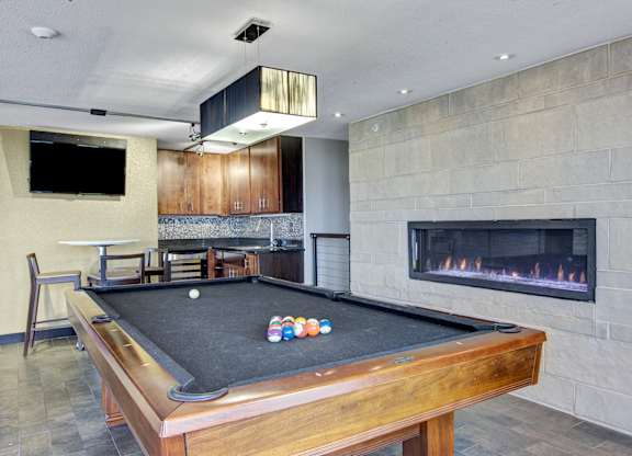 A pool table with a fireplace in the background.