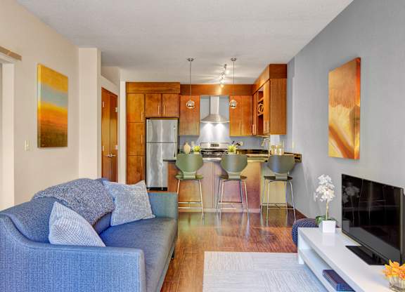 A blue couch with pillows sits in a living room with a bar and a television.