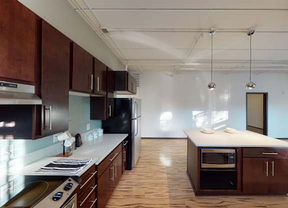 A kitchen with dark wood cabinets and a black refrigerator.