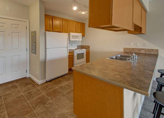 A kitchen with a refrigerator, microwave, and sink.