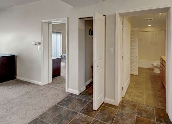 A hallway with a carpeted floor and tiled walls.