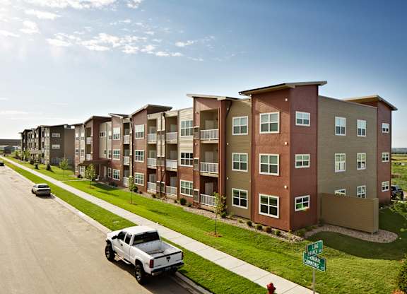 A row of apartment buildings with a white truck parked in front of the first one.