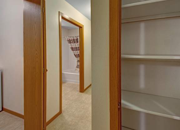A hallway with a mirror and a doorway leading to a closet.
