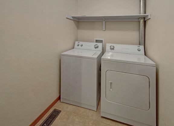 Two white front loading washing machines in a laundry room.