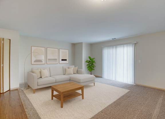 A living room with a couch, a coffee table, and a plant.