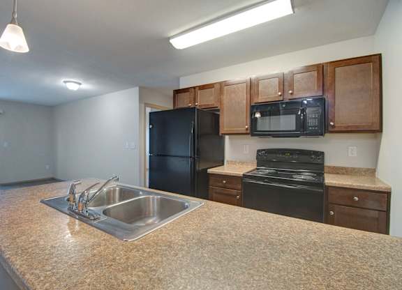 A kitchen with a black refrigerator, microwave, and stove.