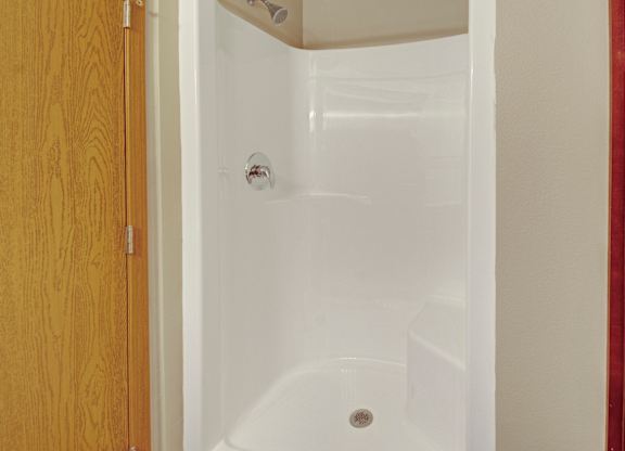 A white bathtub with a shower head and a drain in the middle.