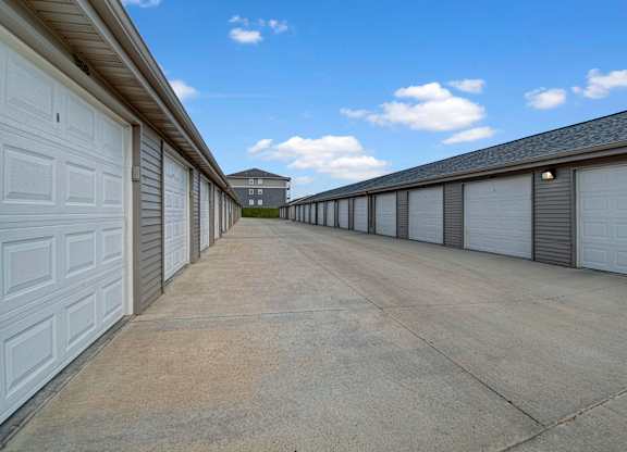 A long row of white garage doors on a sunny day.