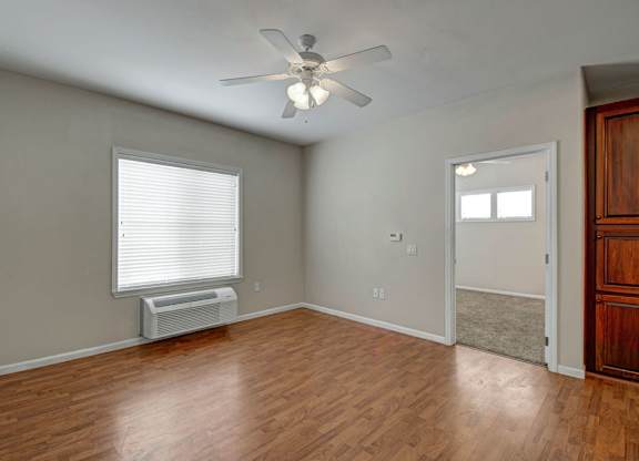 A room with a ceiling fan and a window with blinds.