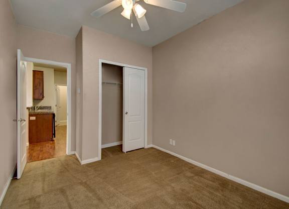 A room with a ceiling fan and carpeted floor.
