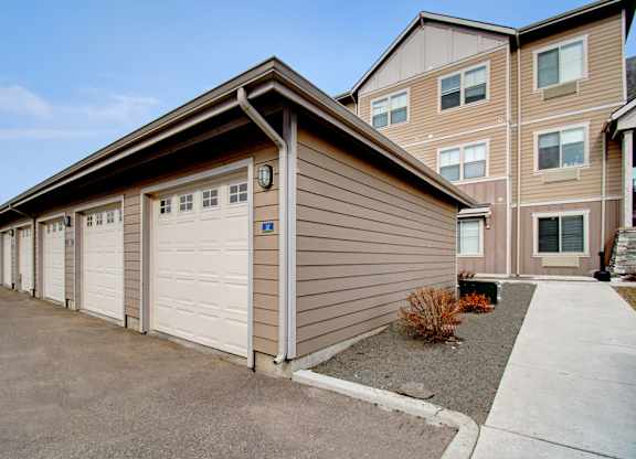 A building with a brown siding and white garage doors.