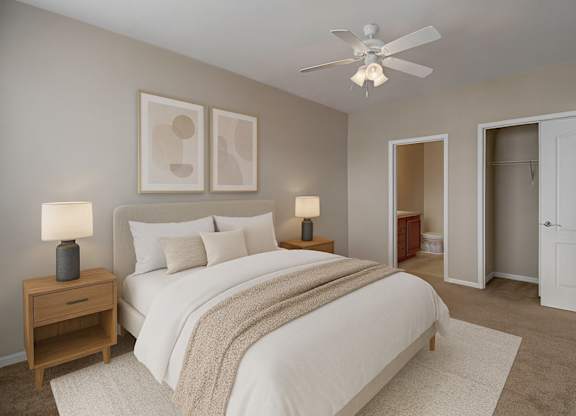 A serene bedroom here at Prairie Vista featuring neutral-toned walls, soft carpet flooring, a queen-sized bed with white bedding and a textured throw, matching bedside tables with lamps, modern abstract wall art, a ceiling fan with light, and direct access to a walk-in closet and ensuite bathroom.