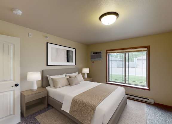 A cozy, well-lit bedroom here at Williston Garden Apartments with soft neutral walls, plush carpet, and a large window that brings in natural light and outdoor views. A neatly made bed with light bedding is paired with matching nightstands and lamps, while simple wall art and clean finishes create a calm, inviting atmosphere.