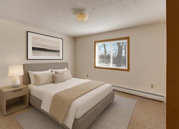 A calm, well-appointed bedroom here at Windscape Apartments featuring soft neutral walls, plush carpet, and a large window that provides natural light and outdoor views. A neatly styled bed with a padded headboard, coordinating nightstand, and simple artwork creates a comfortable, restful sleeping space.