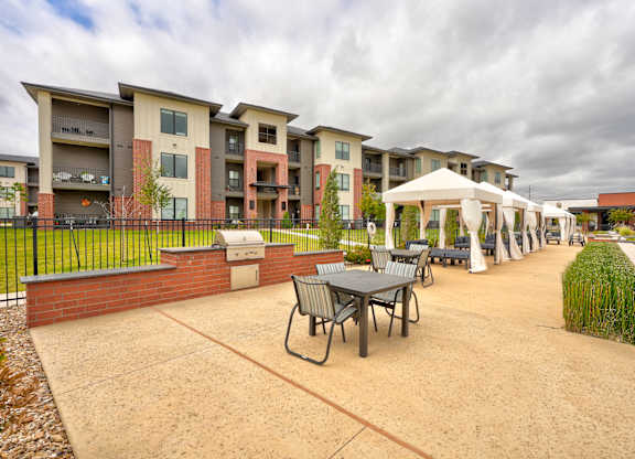 A patio area with tables and chairs in front of apartment buildings.