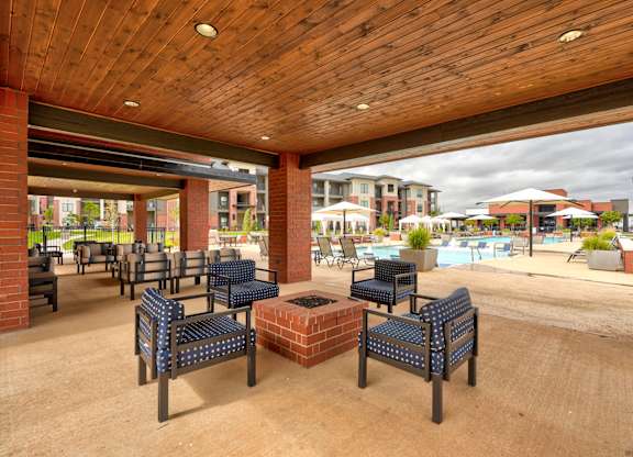 A wooden covered patio with blue cushioned seating.