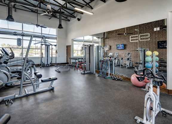 A gym with a variety of exercise equipment including treadmills, weights, and exercise balls.