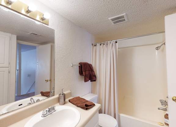 A white bathroom with a towel on the towel rack.