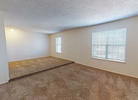 A room with a carpeted floor and a window with blinds.