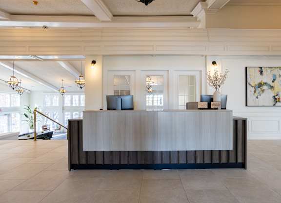 A reception desk with a plant on it and a painting on the wall.