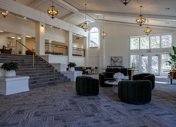 A large, well-lit room with a staircase and comfortable seating areas.