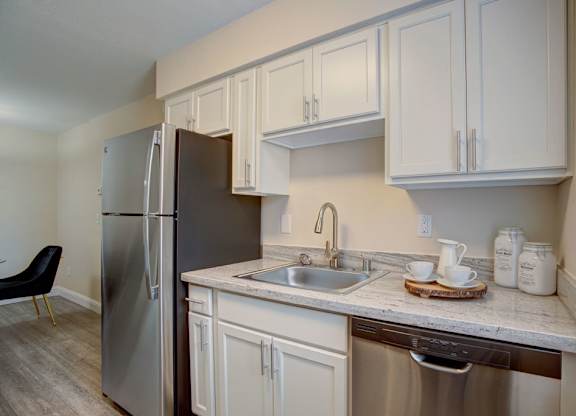 A kitchen with white cabinets and a stainless steel refrigerator.