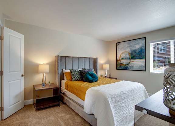 A bedroom with a bed, nightstands, and a painting on the wall.