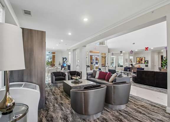 A modern living room with a grey carpet and a variety of seating options.