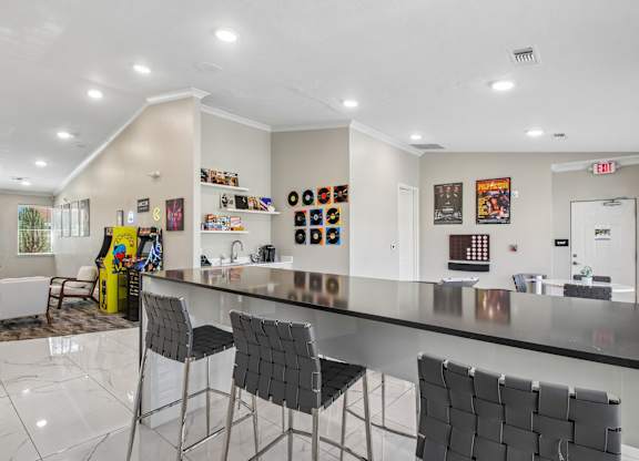 A modern kitchen with a long counter and chairs.