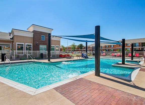 A large outdoor swimming pool with a blue shade structure.