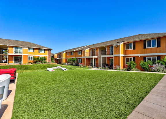 A sunny day at a residential complex with green lawns and orange buildings.