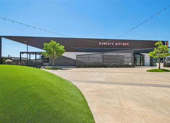 A building with a green lawn in front and a sign that says "Ramsay's Kitchen".