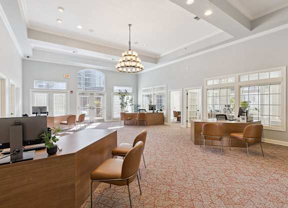 A bright leasing office here at Lincoln at Central Park with wood service desks, guest seating, and large windows with blinds. A decorative chandelier and high ceilings create an open, welcoming, and professional leasing environment.