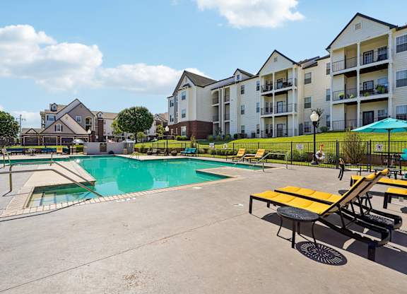 A swimming pool surrounded by a concrete patio and a yellow picnic table.