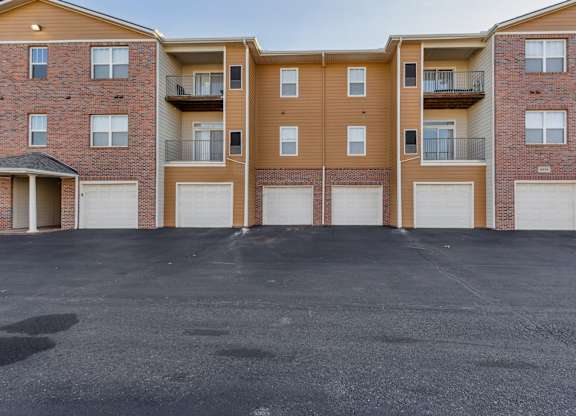 A parking lot in front of a brick apartment building.