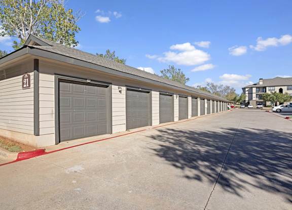 A row of detached garages here at Stoneleigh on May with individual roll-up doors and a clean paved drive. The layout offers convenient parking and extra storage in a well-maintained community setting.