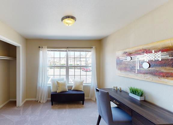A room with a desk, chair, and a window with curtains.