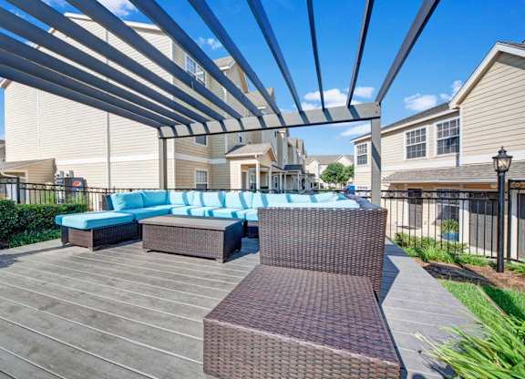 A patio with a blue couch and a brown bench under a white canopy.