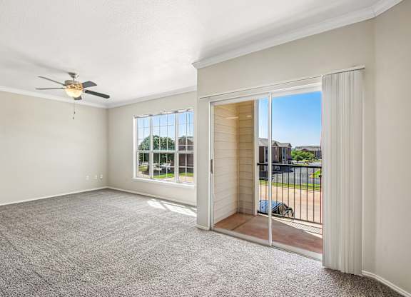 A room with a ceiling fan and sliding glass doors.