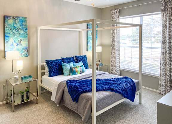 A bedroom with a white bed and blue pillows.