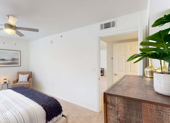 A bedroom with a bed, a ceiling fan, and a painting on the wall.
