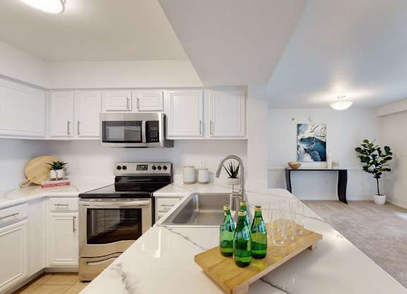 A kitchen with white cabinets and a green bottle on the counter.