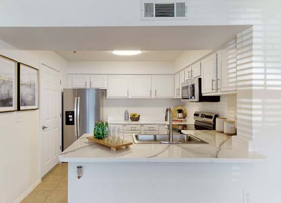 A kitchen with white cabinets and a stainless steel refrigerator.