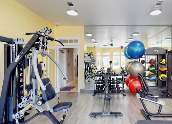 A gym with a variety of equipment including weights, machines, and a mirror.