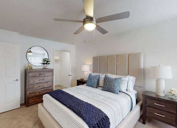 A bedroom with a bed, dresser, and ceiling fan.