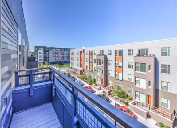 View from a balcony overlooking modern apartment buildings with colorful facades under a clear blue sky at Stitchweld Apartments.